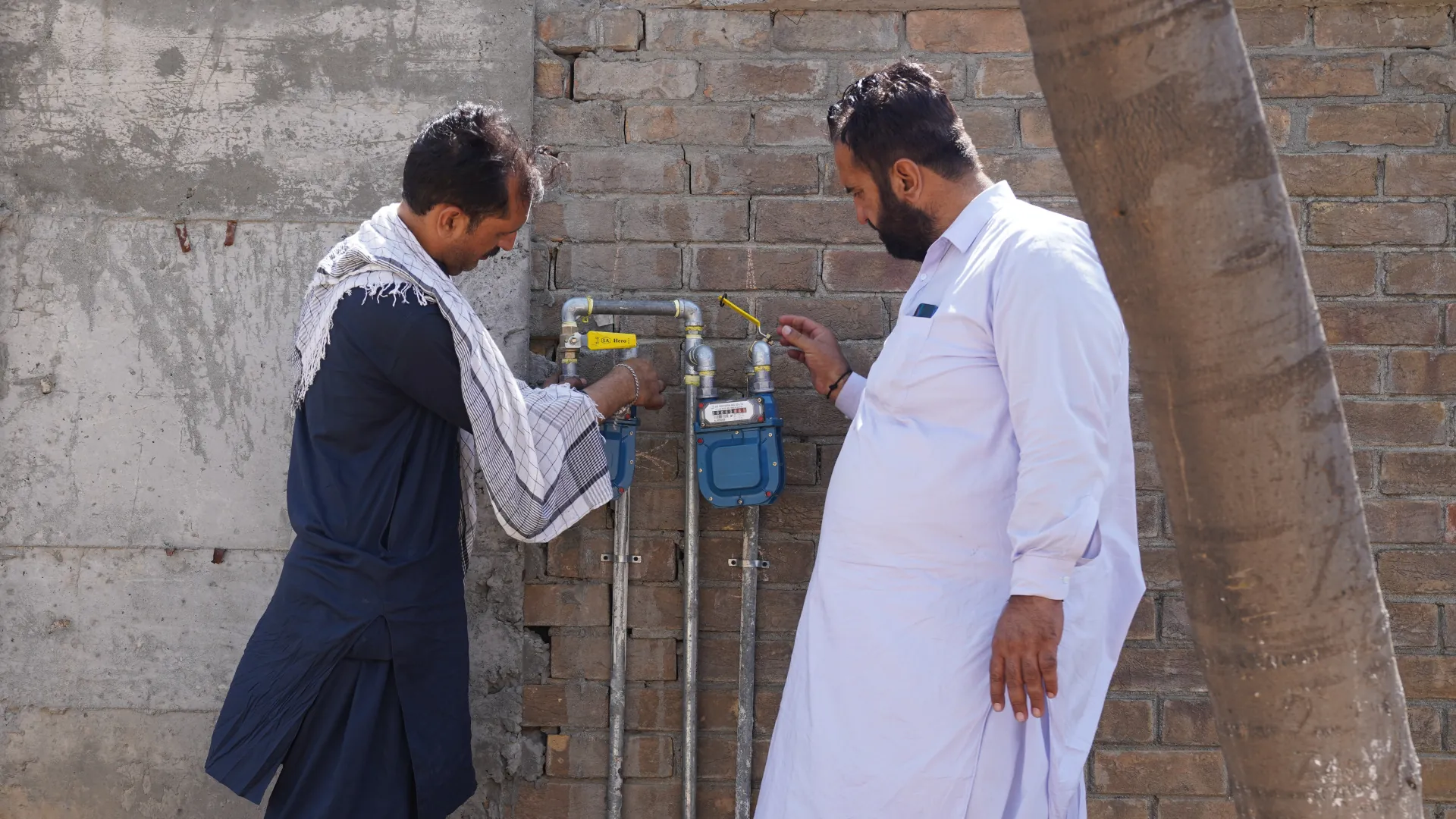 Two men fitting gas meters to a wall