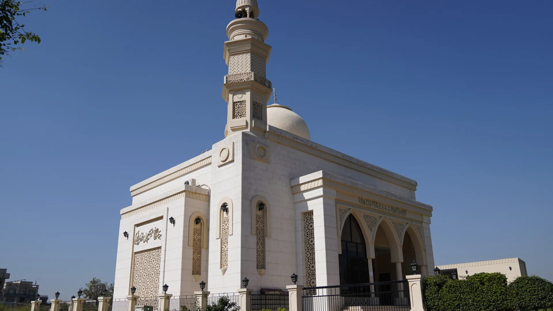 A white mosque with a minaret and an arched entrance