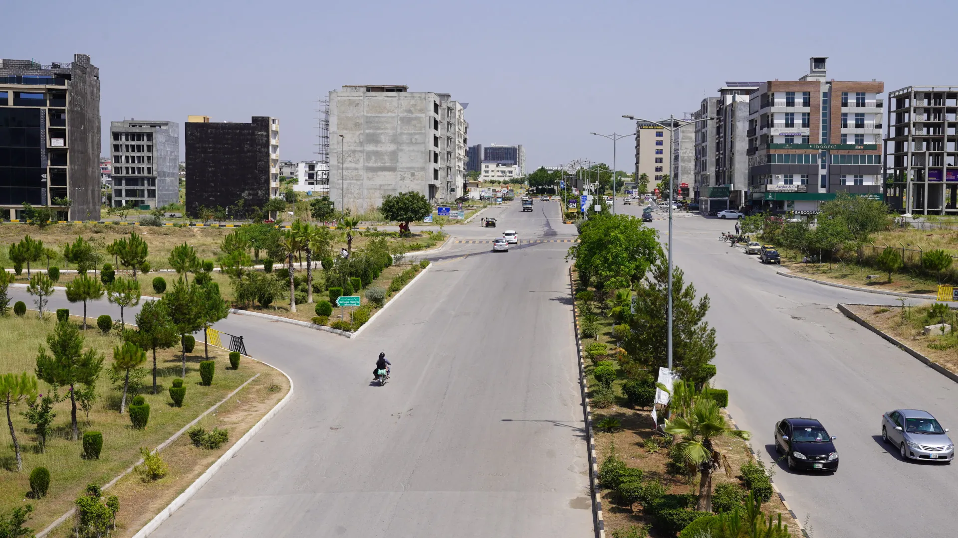 A divided avenue with planted verges between commercial buildings