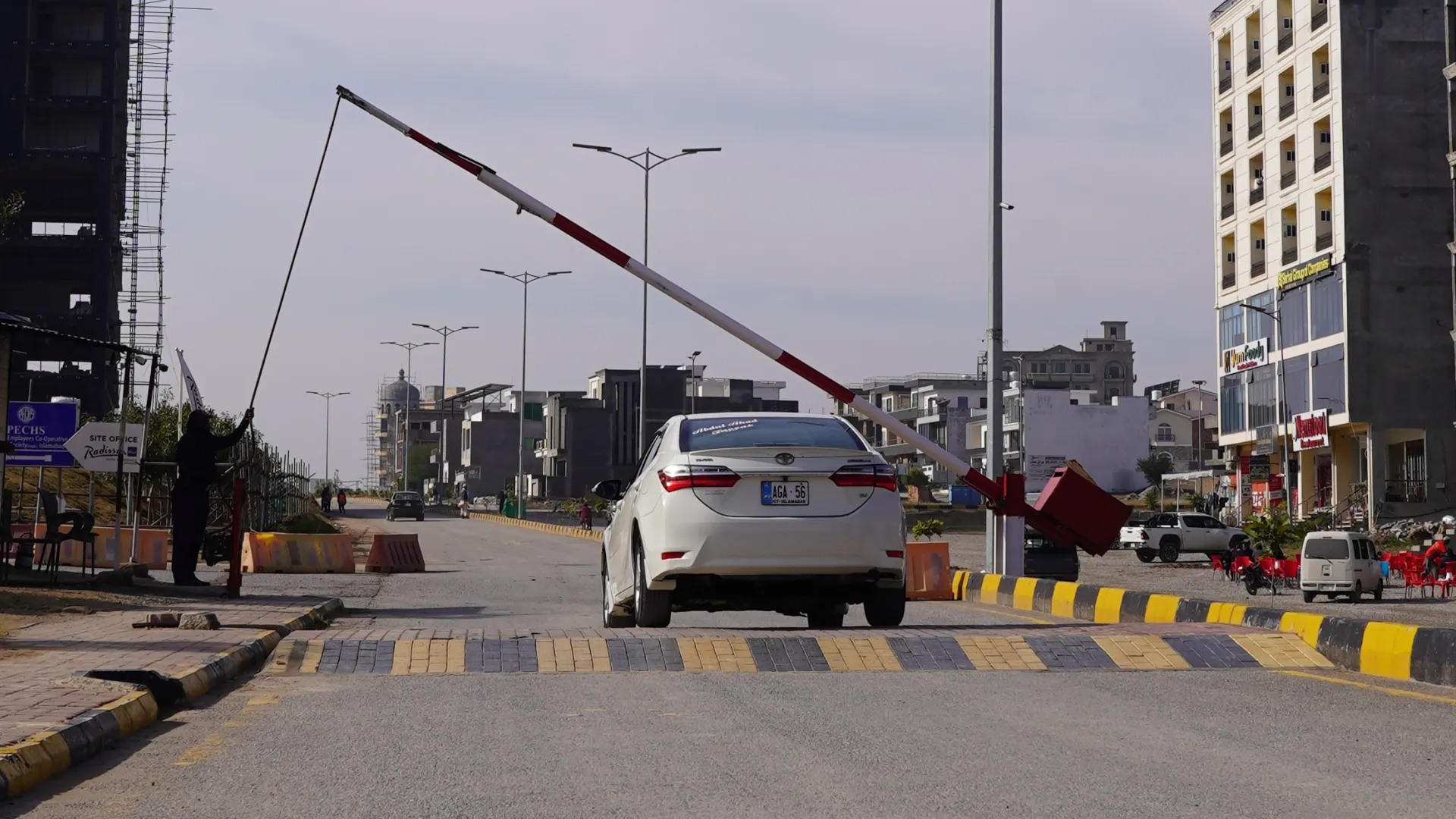 A guard raising the barrier for a car at an entrance gate