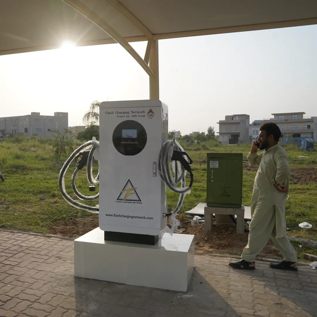 A pump unit under a canopy with a man walking past