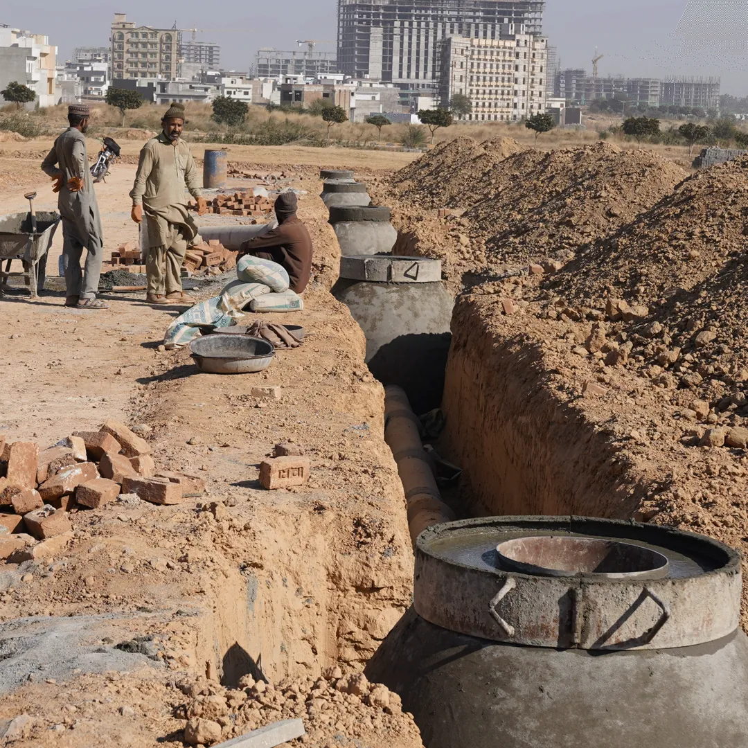 Workers laying pipes in a trench