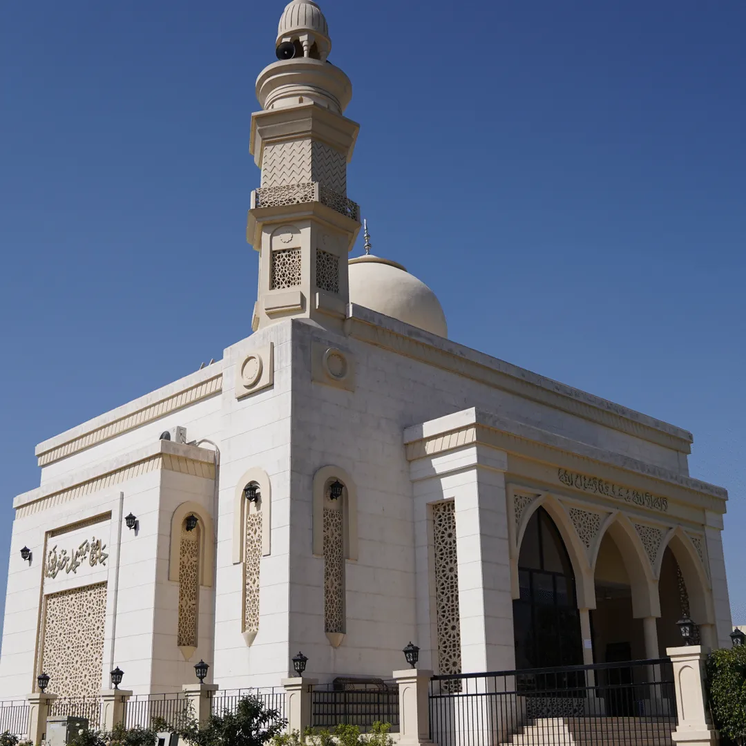 A white mosque with a minaret and a dome